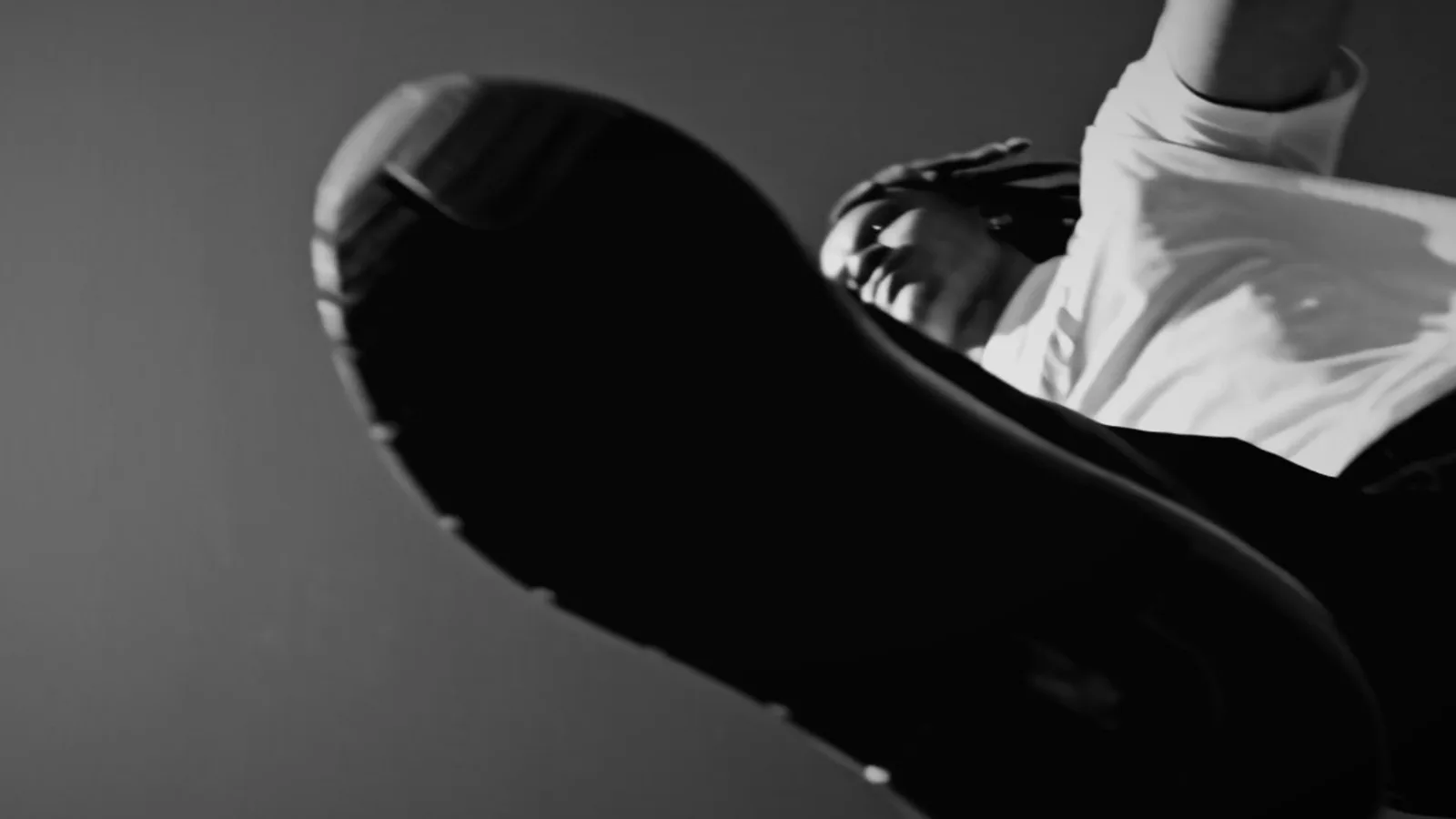 Low-angle figure stepping toward the camera, in black and white